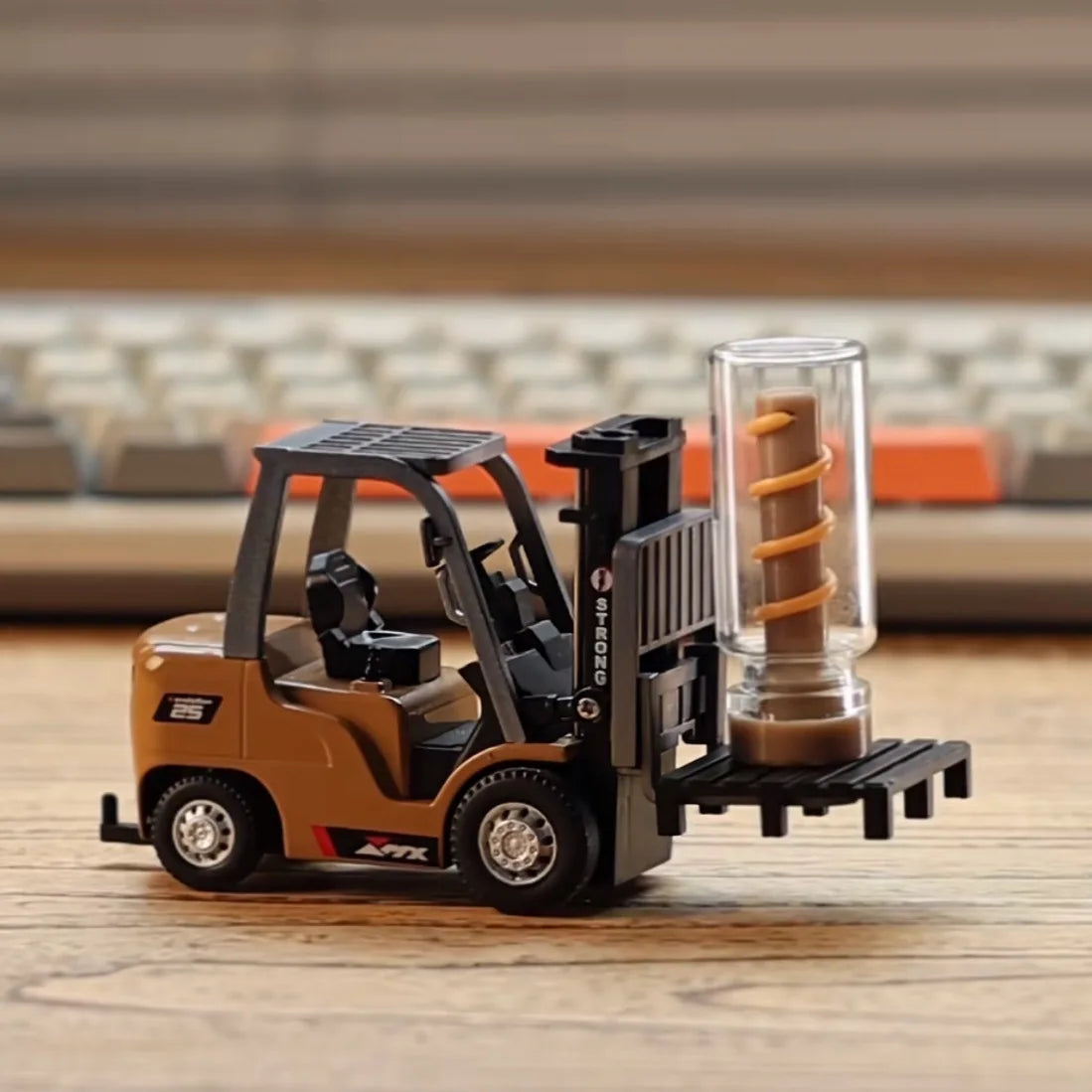Miniature forklift toy in brown and black lifting a small clear container on wooden surface