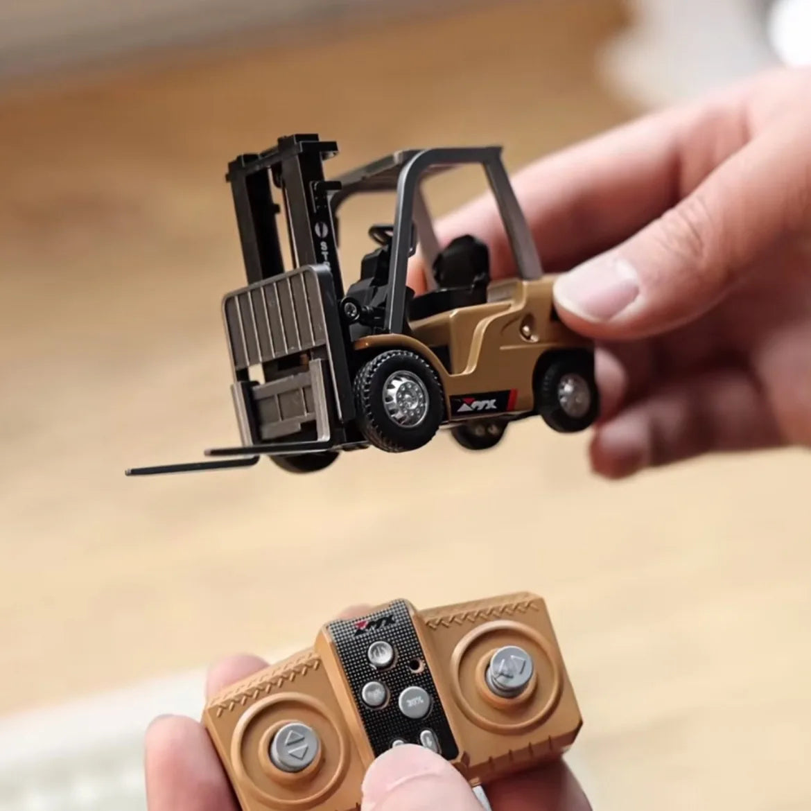 Hands holding a miniature forklift toy with a remote control for interactive play